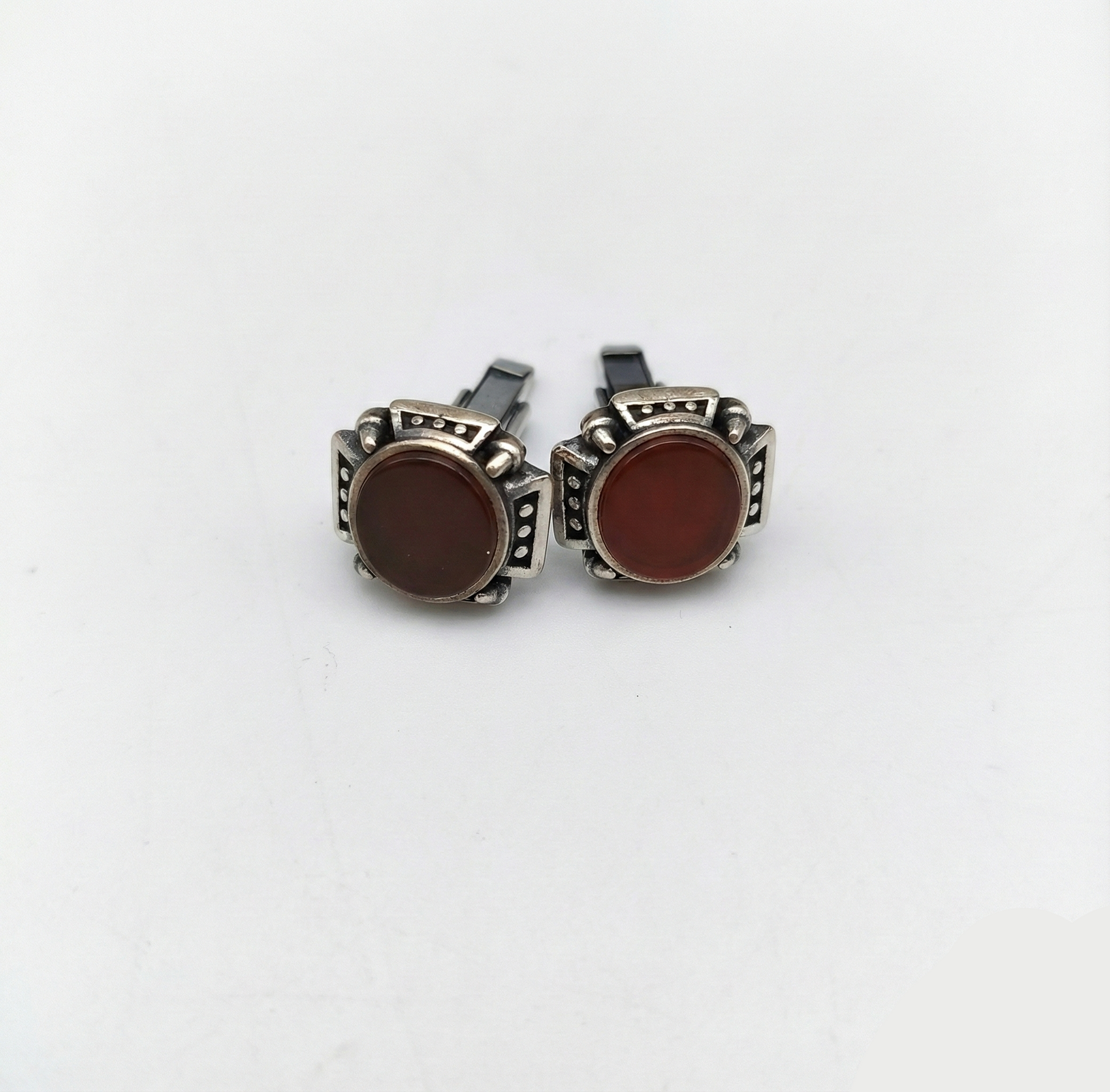 Pair of cufflinks with brown stones and silver detailing on a white background