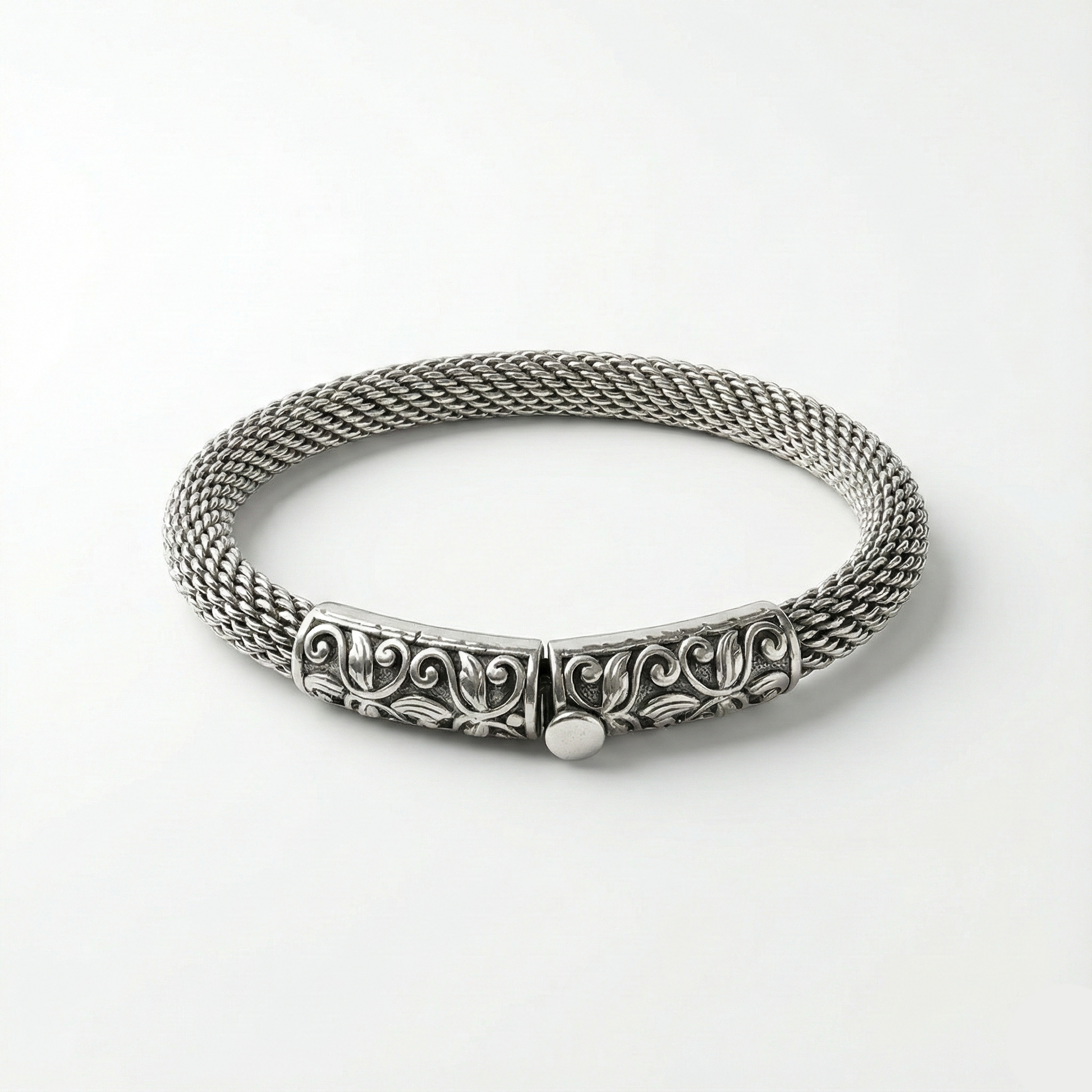 Silver bracelet with intricate design on a white background