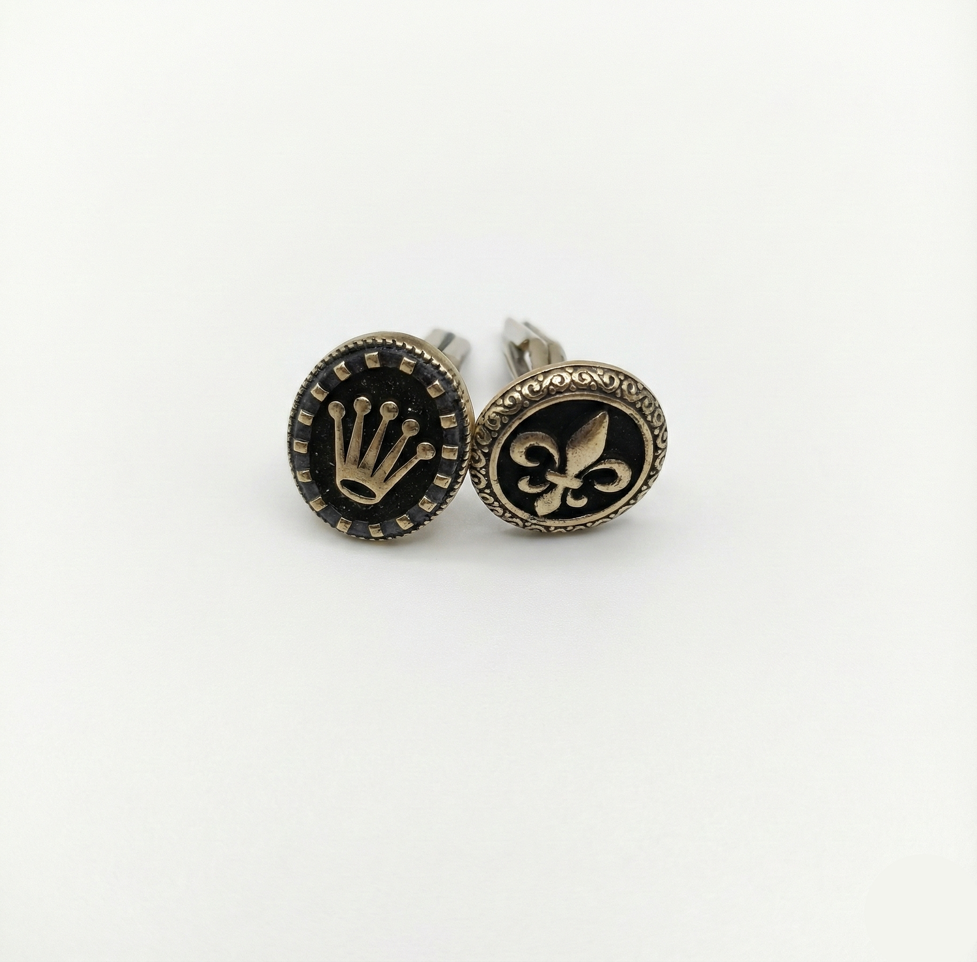 Pair of cufflinks with decorative symbols on a white background