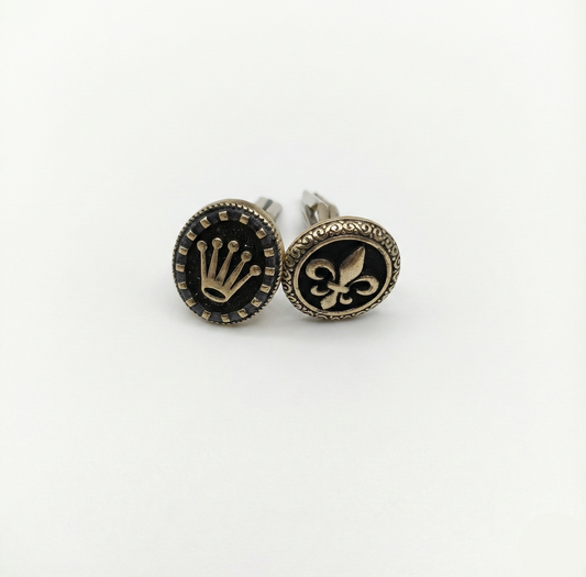 Pair of cufflinks with decorative symbols on a white background