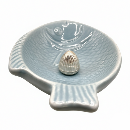 Ceramic shell-shaped dish with a small shell on a white background