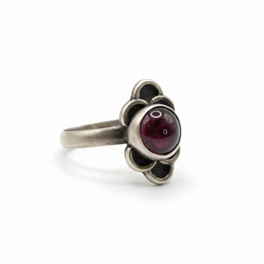 Silver ring with a red gemstone on a white background