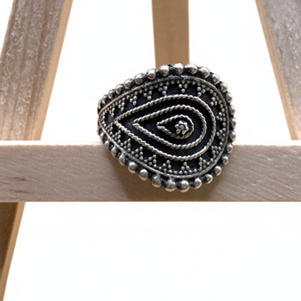 Decorative black and silver brooch on a wooden surface