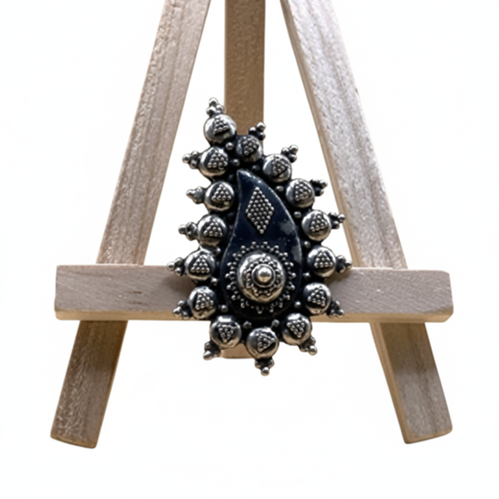 Decorative metal brooch on a small wooden easel against a white background