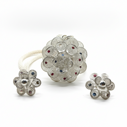Silver jewelry set with floral designs and gemstones on a white background