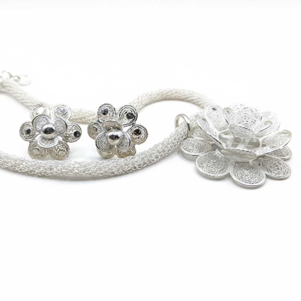 Silver floral earrings and necklace set on a white background