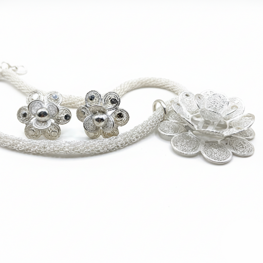 Silver floral earrings and necklace set on a white background