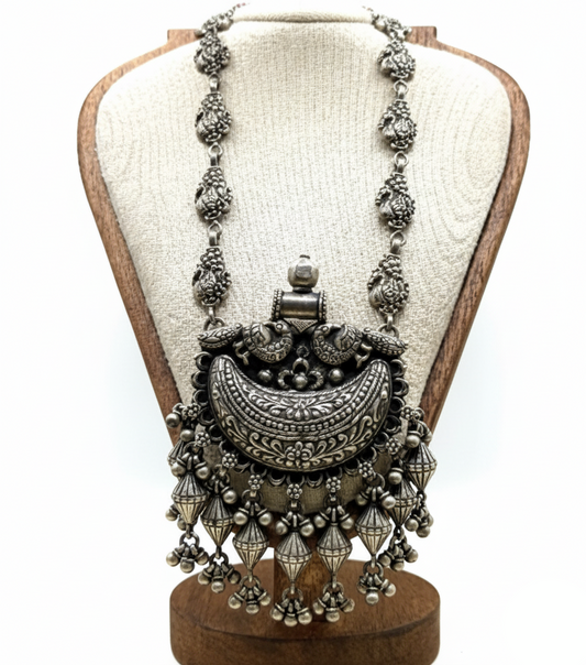 Ornate silver necklace on a wooden mannequin bust with a white background