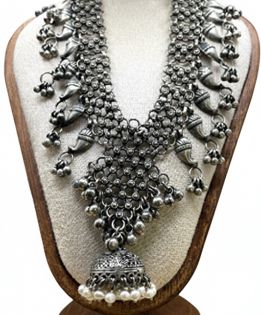 Silver necklace with intricate designs and pendants on a wooden stand.