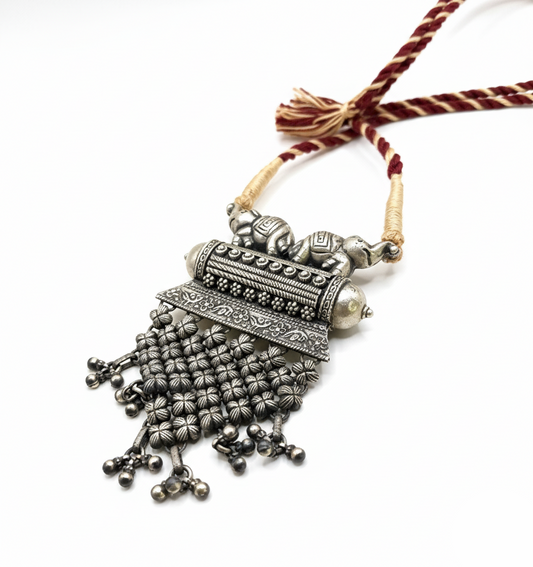 Ornate silver necklace with tassels on a white background