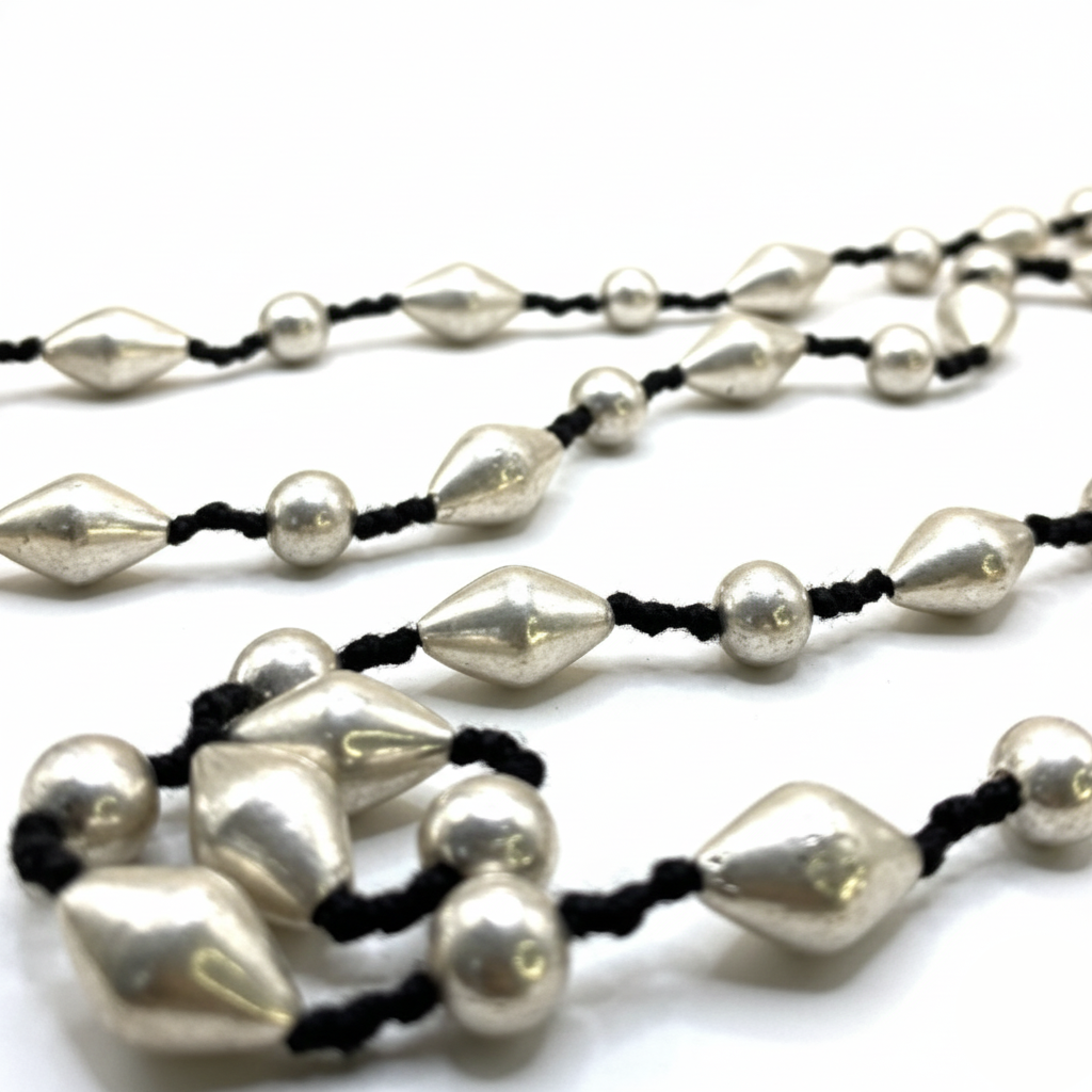Necklace with silver beads and black cord on a white background