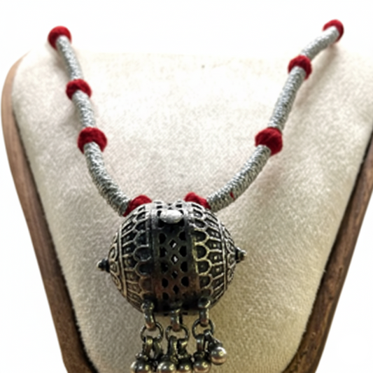 Silver necklace with red beads on a white cushion