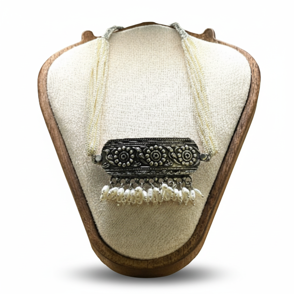 Necklace with an ornate silver pendant on a wooden and fabric display