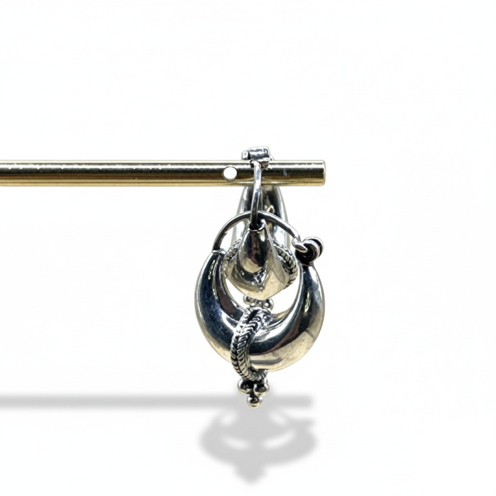 Silver brooch with intricate design on a white background