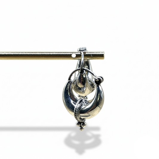 Silver brooch with intricate design on a white background