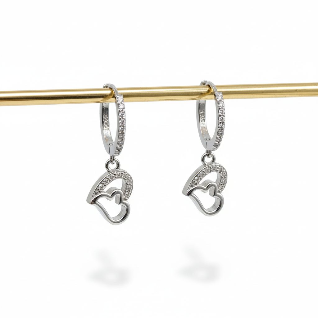 Silver heart-shaped earrings on a gold rod against a white background