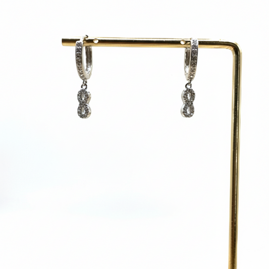 Silver hoop earrings with dangling charms on a gold stand against a white background