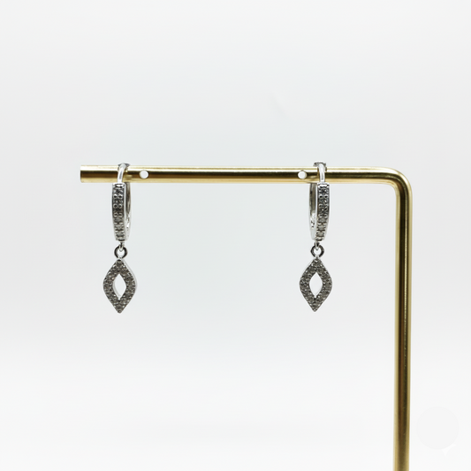 Pair of silver earrings on a gold stand against a white background