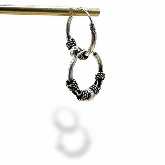 Silver hoop earrings with intricate designs on a white background