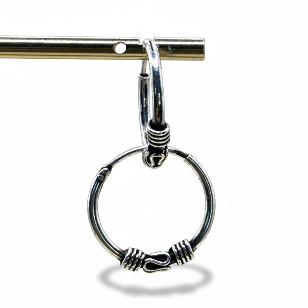 Silver hoop earring with intricate design on a white background