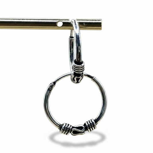 Silver hoop earring with intricate design on a white background