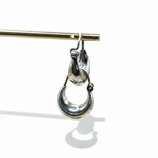 Silver earring hanging from a gold rod on a white background