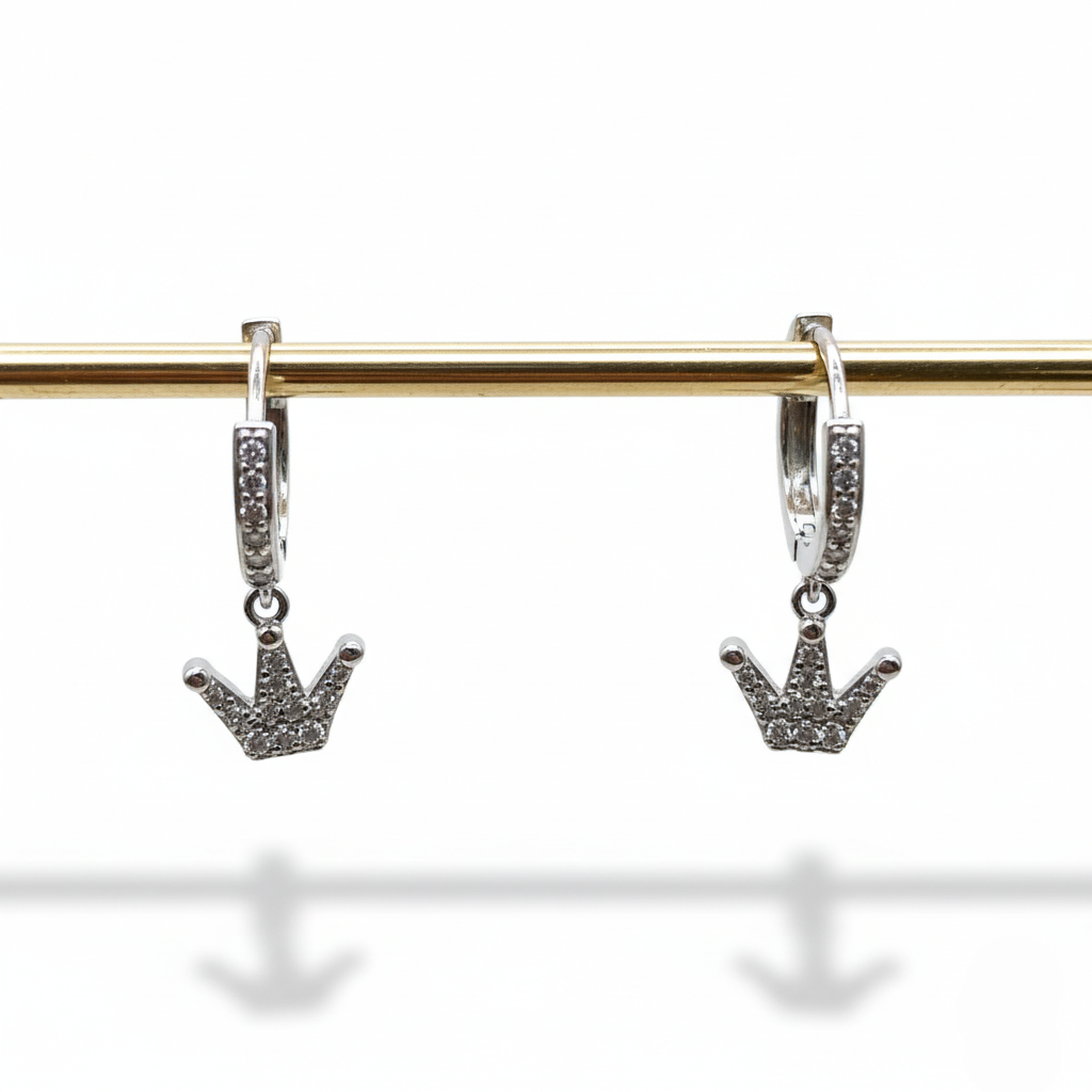 Silver hoop earrings with crown-shaped charms on a gold rod against a white background