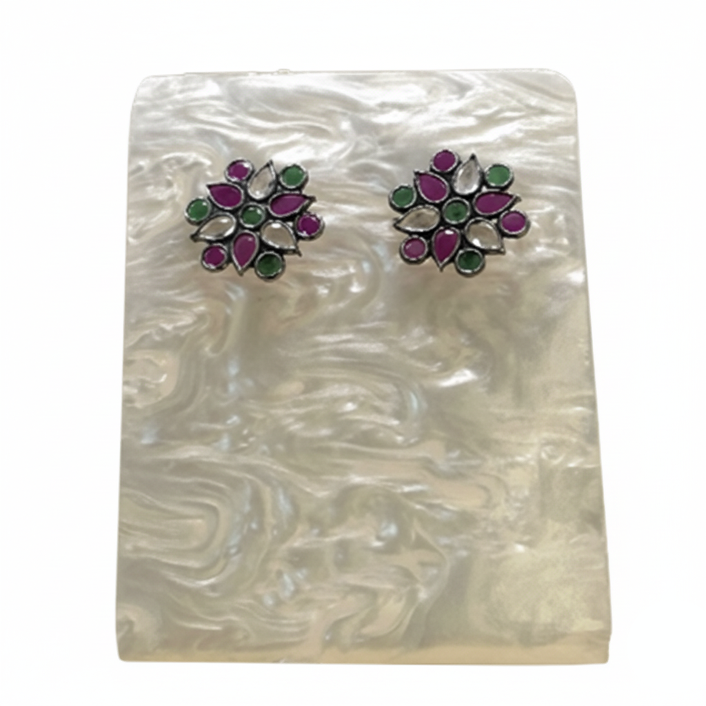Pair of floral earrings with purple and green stones on a white background