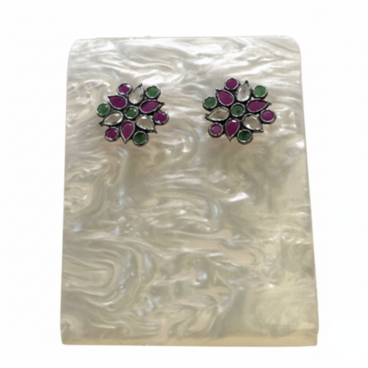 Pair of floral earrings with purple and green stones on a white background