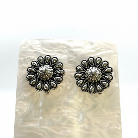 Pair of silver floral earrings on a textured white surface