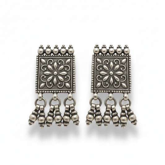 Pair of silver earrings with floral designs and dangling beads on a white background