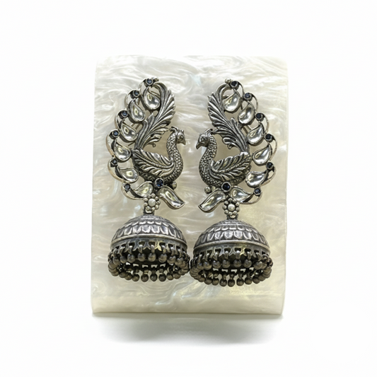 Pair of silver peacock feather earrings on a white background