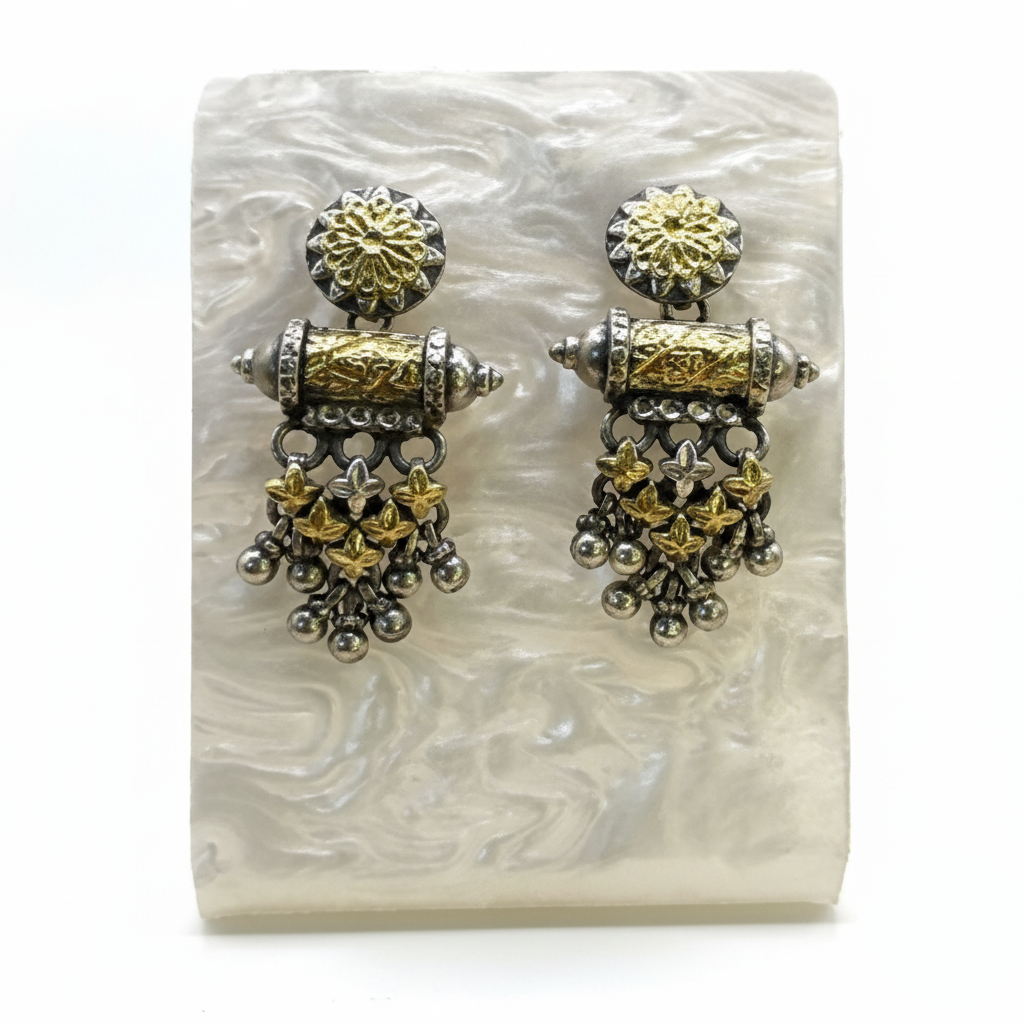 Pair of gold and silver earrings on a white stone surface