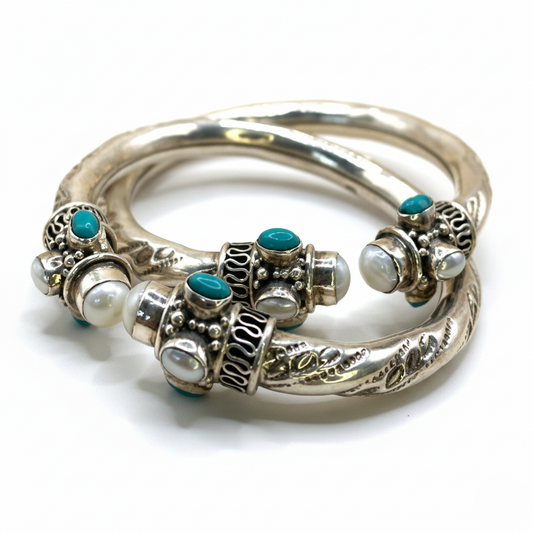 Silver bangles with turquoise and pearl-like stones on a white background