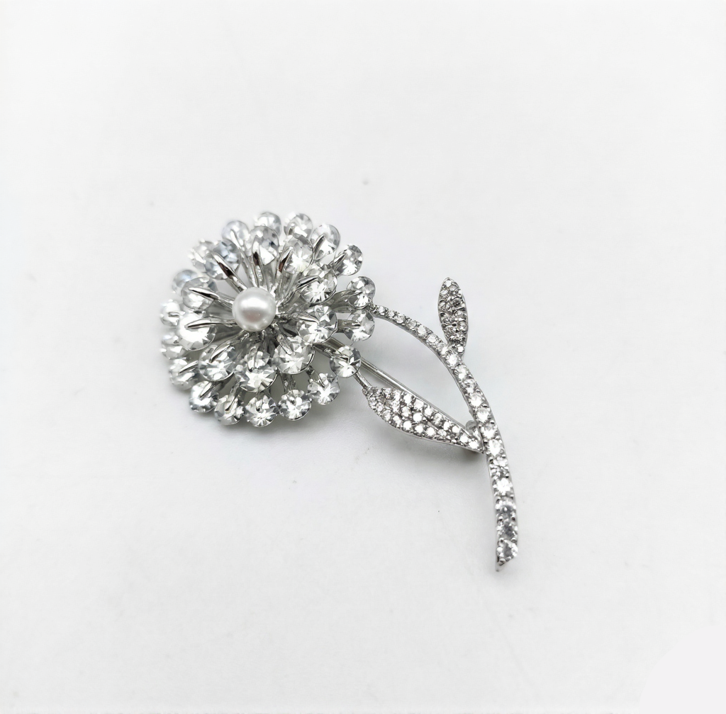 Silver flower-shaped brooch with a central pearl on a white background