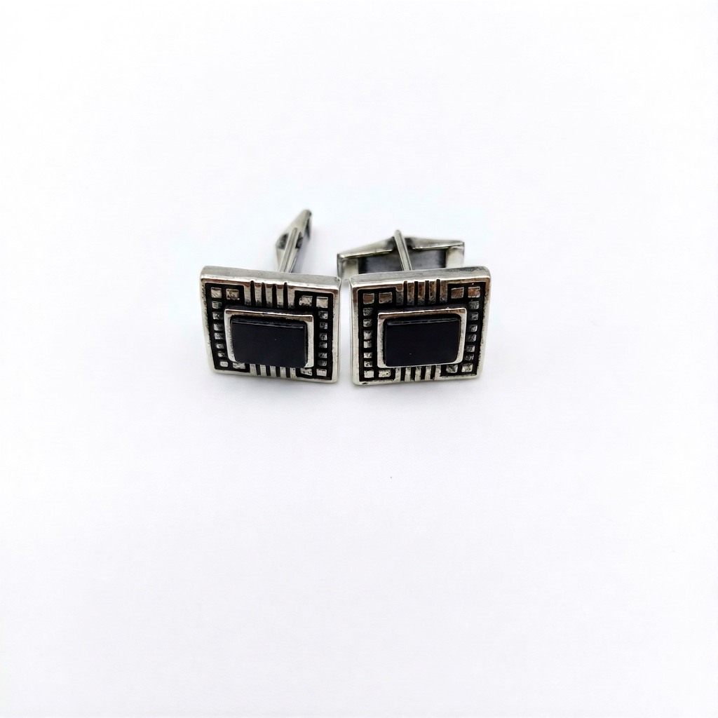 Pair of silver cufflinks with black stones on a white background
