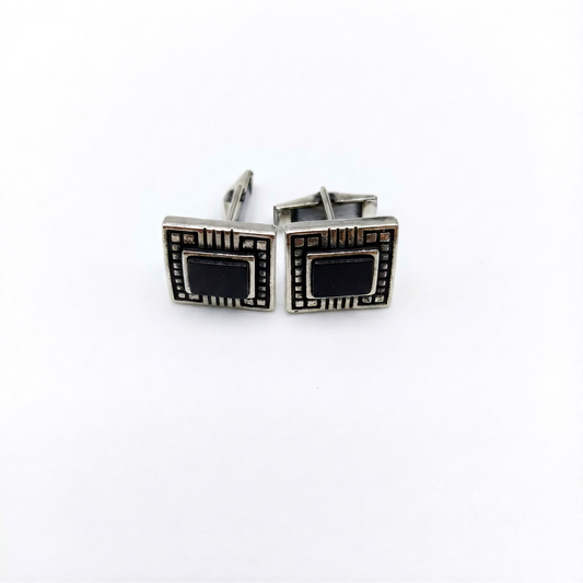 Pair of silver cufflinks with black stones on a white background