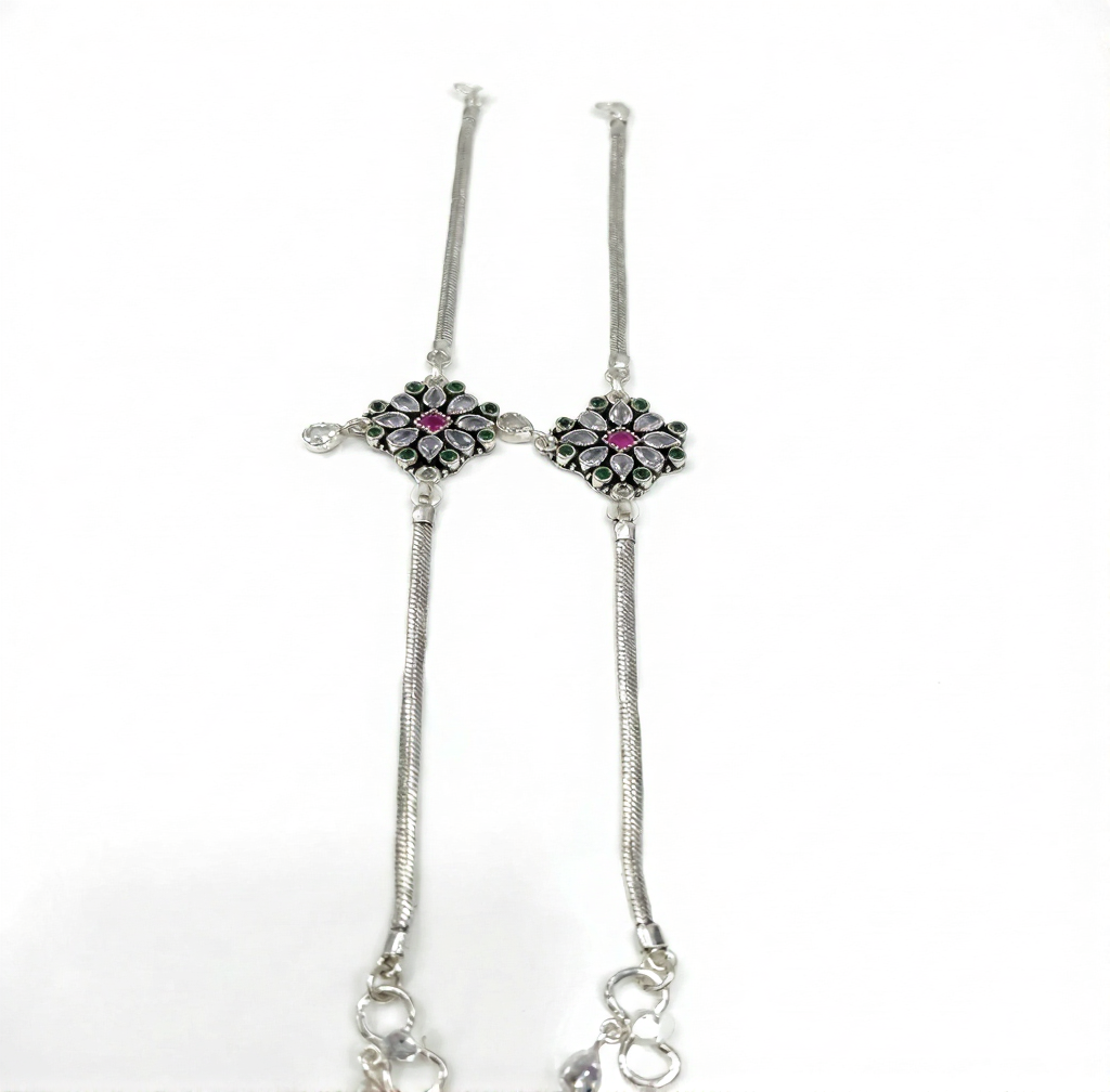 Silver bracelet with floral designs and pink stones on a white background