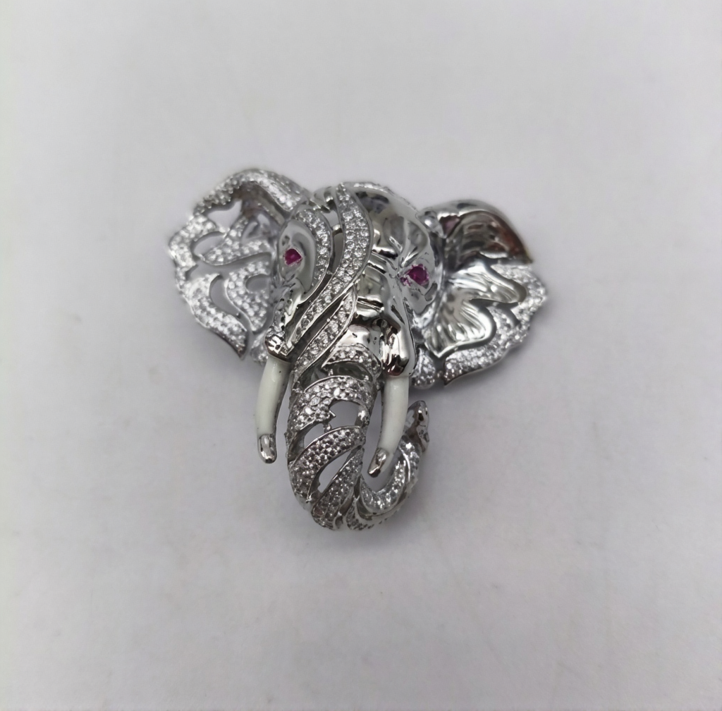 Silver elephant head brooch with gemstone eyes on a light gray background